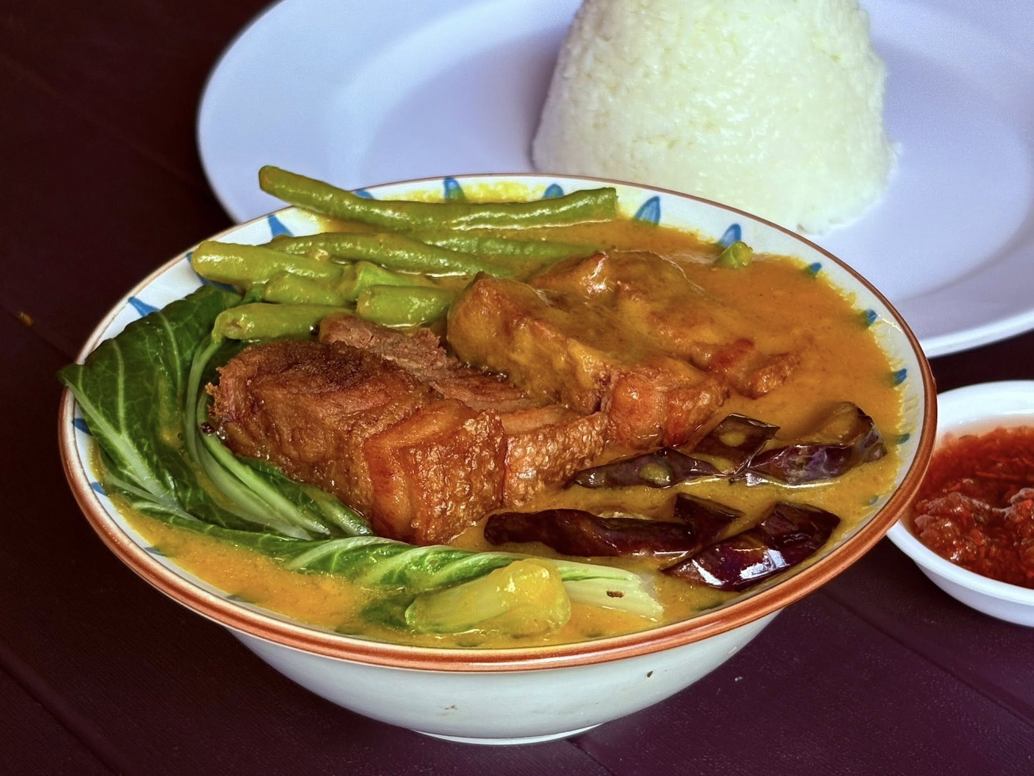 Kare-kare bowl with crispy lechon kawali, vegetables, and rice